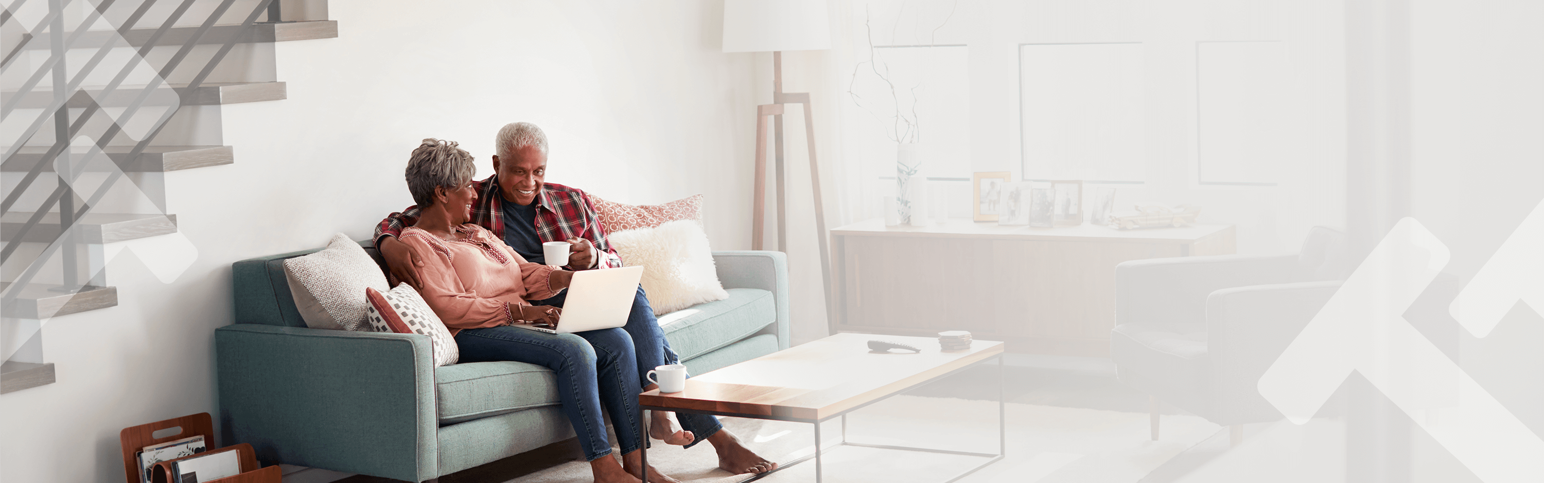 A couple sitting next to each other on their couch with their laptop open